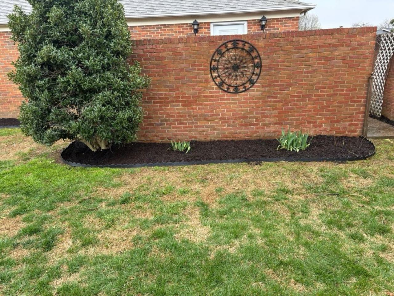 Mulch bed and decorative feature along a brick wall